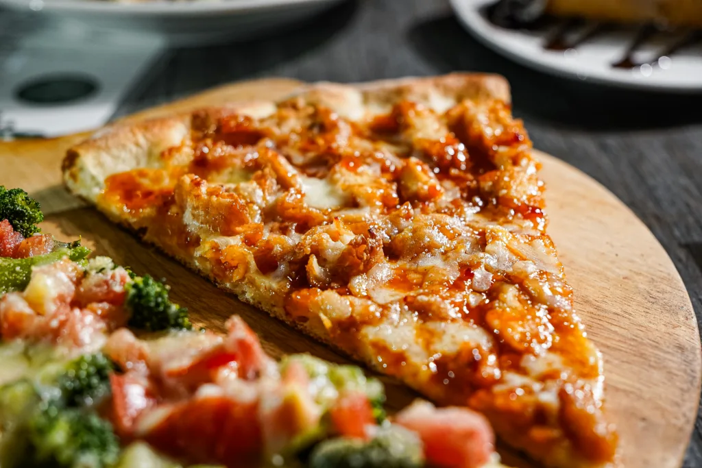 Pizza slice with browned meat and melted cheese