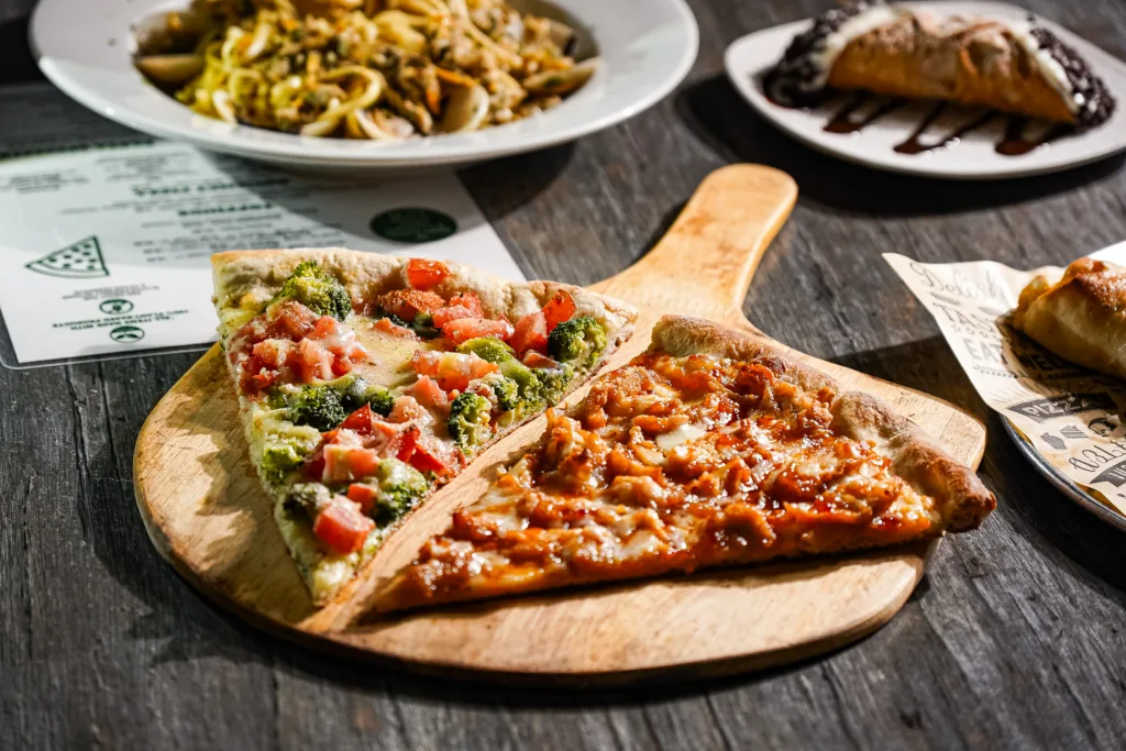 Two different pizza slices on a wooden serving paddle